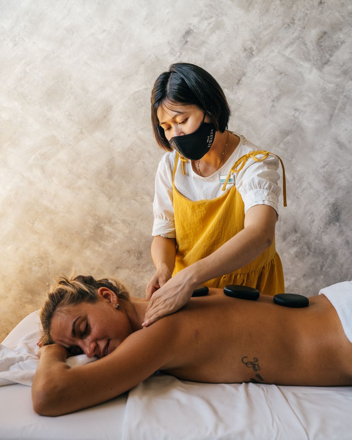 Therapist placing heated basalt stones along a client's back